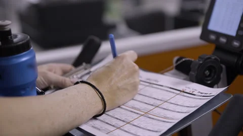 Gym patron records exercise performance statistics with pen and paper Stockbeeldmateriaal 138448501