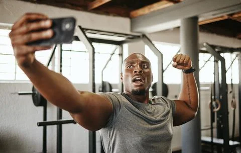 Gym selfie, smartphone and man flexing arm muscle for a post gyming pump Stock Photos