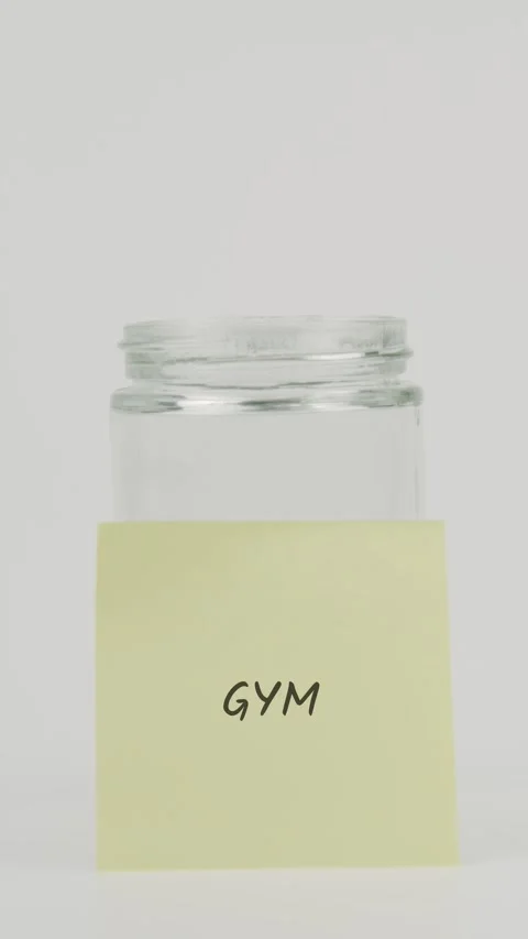 Gym text or word on yellow sticky note attached to glass jar with hand Stock Footage 311734335