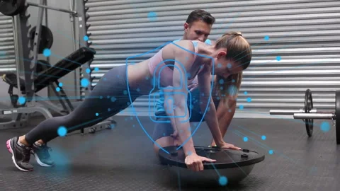 Gym trainer cueing client maintaining Bosu plank for strength with particles Stock Footage 311697951