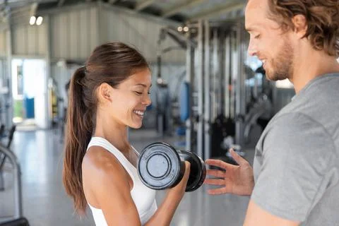 Gym workout personal trainer man helping woman having the right body posture to Stock Photos