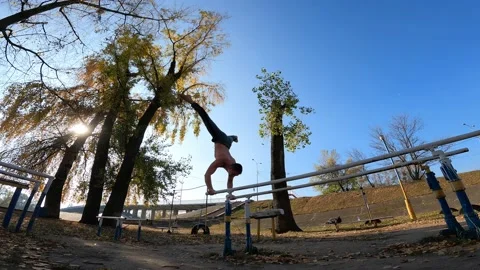 Gymnast does tricks on parallel bars outdoor. Concept of willpower, motivation Stock-Footage 166364918