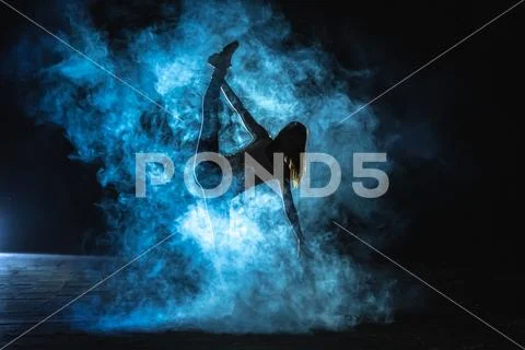 The gymnast doing vertical split in the smoke on the dark background Stock Photos