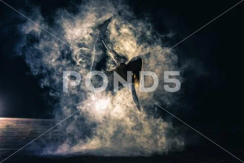 The gymnast doing vertical split in the smoke on the dark background Stock Photos