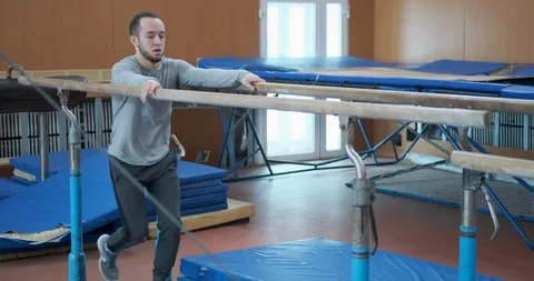 Gymnast doing workout on parallel bars at gym Stock-Footage 104995180
