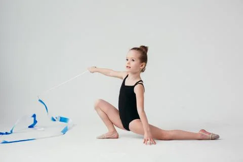 Gymnast performs the exercise standing on one leg. White wall on background. Foto stock