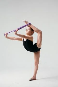 Gymnast performs the exercise standing on one leg and using equipment. Stock Photos