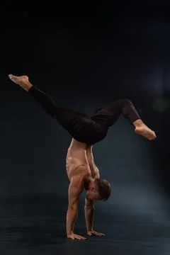 Gymnast performs an impressive handstand on one hand showcasing strength and Stock Photos