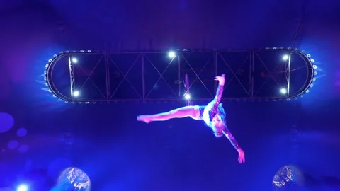 A gymnast quickly rotates around herself on a gymnastic hoop in the circus. Stock Footage 308471132