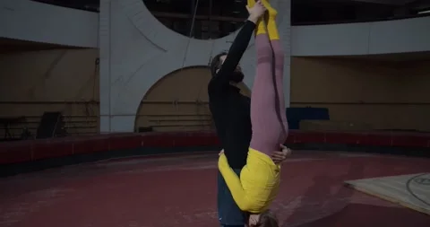 Gymnastics tricks by two athletic people at the circus, split by a woman, 4k Stock Footage 147191820