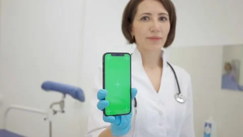 Gynecologist shows an iPhone 12 with a chromakey. The doctor in the Stock Footage