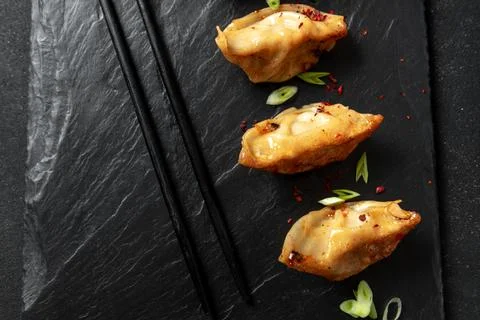 Gyoza or Jiaozi Asian fried dumplings with soy sauce, and green onions on a Stock Photos