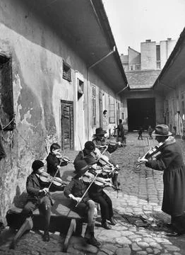 Gypsy children being taught to play the violin in a courtyard of one of the poor Stock Photos