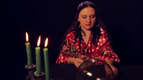 Gypsy fortune teller at the table by candlelight spreads fortunetelling cards Stock Footage 99868725