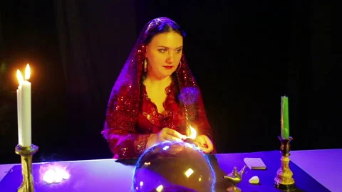 A gypsy in the magic salon is engaged in magic with a crystal ball, from which Stock Footage 107785325