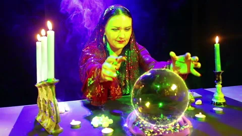 Gypsy in the magic salon is engaged in magic with a crystal ball, from which the Stock Footage 107785481