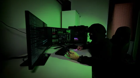 Hacker Analyzes Data on Foldable Phone and Computer Screens in Dark Room Stock Footage 317079601