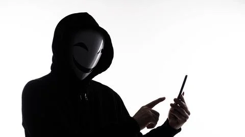 Hacker Anonymous and face mask with smartphone in hand. Stockfoto's
