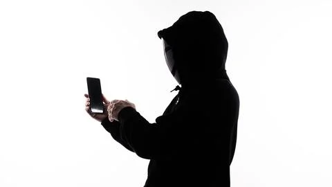 Hacker Anonymous and face mask with smartphone in hand. 스톡 사진