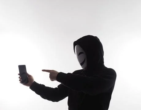 Hacker Anonymous and face mask with smartphone in hand. Stockfoto's