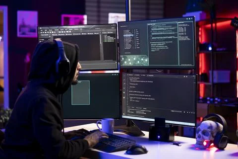 Hacker in apartment listening music, coding malware Foto stock
