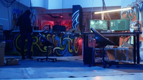 Hacker arriving in underground base, looking at spray cans Stock Footage 319570112