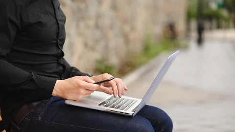 Hacker in black types on modern laptop holding phone close Stock-Footage 111611533