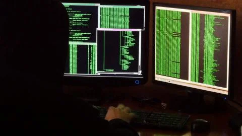 Hacker breaking code. Criminal hacker with black hood penetrating network system 스톡 사진