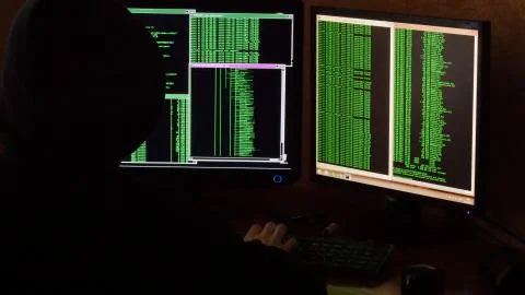 Hacker breaking code. Criminal hacker with black hood penetrating network system Stock Photos