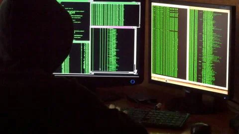 Hacker breaking code. Criminal hacker with black hood penetrating network system Stock Photos
