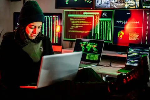 Hacker breaking into corporate network using laptop and multiple screens Stock Photos