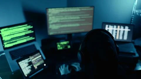 Hacker breaks into company data servers in dark atmosphere and multiple displays Stock Photos