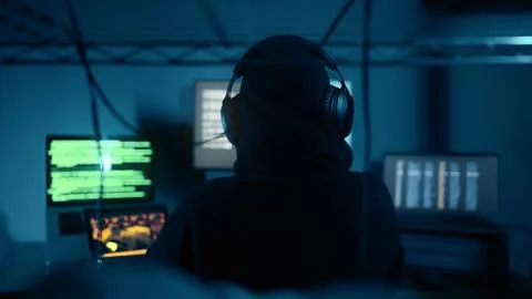 Hacker breaks into company data servers in dark atmosphere and multiple displays 스톡 사진