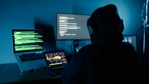 Hacker breaks into company data servers in dark atmosphere and multiple displays Stock-Fotos