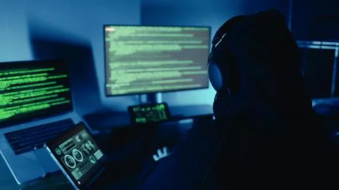 Hacker breaks into company data servers in dark atmosphere and multiple displays Foto stock