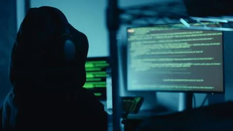 Hacker breaks into company data servers in dark atmosphere and multiple displays Foto stock