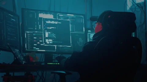 Hacker in cap and glasses coding on computer for cyber crime Stock Footage 257383129