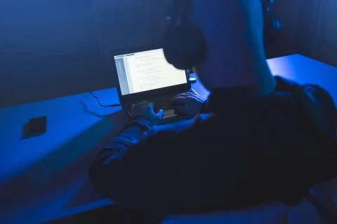 Hacker with coding on laptop computer in dark room Foto stock