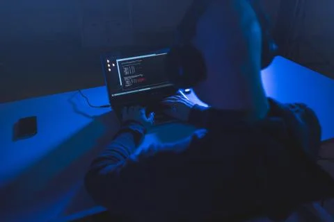 Hacker with coding on laptop computer in dark room Foto stock