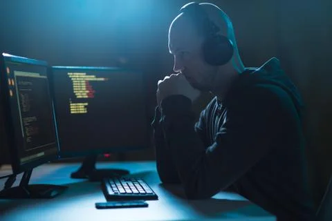 Hacker with coding on laptop computer in dark room Foto stock