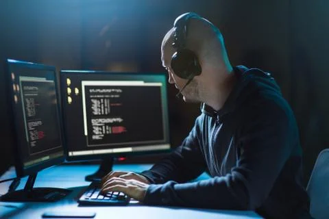 Hacker with coding on laptop computer in dark room 写真素材