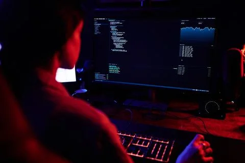 Hacker coding malware at computer in dark room Stock Photos