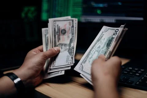 Hacker counting dollars at hideout Foto stock