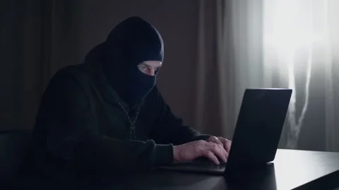 Hacker cracker in the hood in a dark room using computer virus program for cyber Stock Footage 138839197