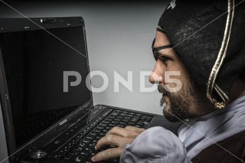 Hacker, cyber criminal with pirate clothes, attempt to hack a laptop Stock Photos