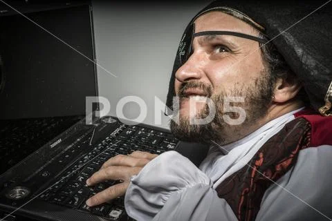 Hacker, cyber criminal with pirate clothes, attempt to hack a laptop Stock Photos