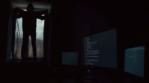 Hacker in dark hood standing on the windowsill and covering windows with black Stock Footage 72325320
