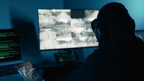 A Hacker in the dark room surrounded computer. Hacking and malware. Cyber crime. Stock Photos