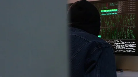 A hacker does something on the computer around the corner and then turns around. 库存影片 74714943