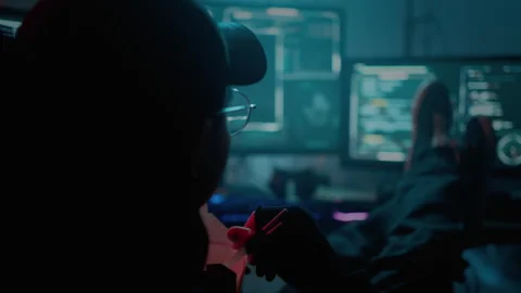 Hacker eating noodles while sitting at table with computers Stock Footage 257382439